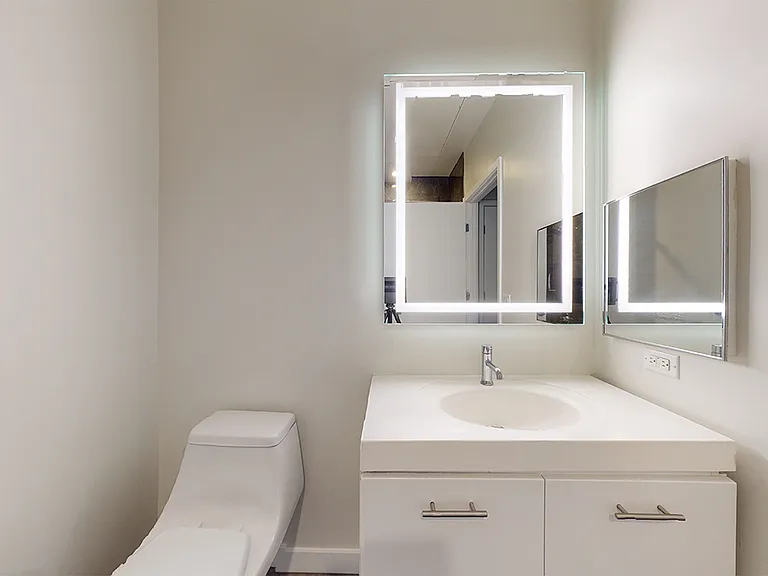 Apartment bathroom with LED vanity mirror.