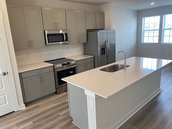 Kitchen with gray cabinets, quartz countertops, island with sink, and pantry. All chrome Whirlpool kitchen appliances included.