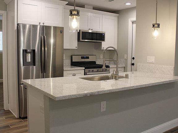 Newly renovated kitchen has granite counters, breakfast bar, stainless steel appliances-including refrigerator! Door to the right enters garage. Door on the left is secondary bedroom.