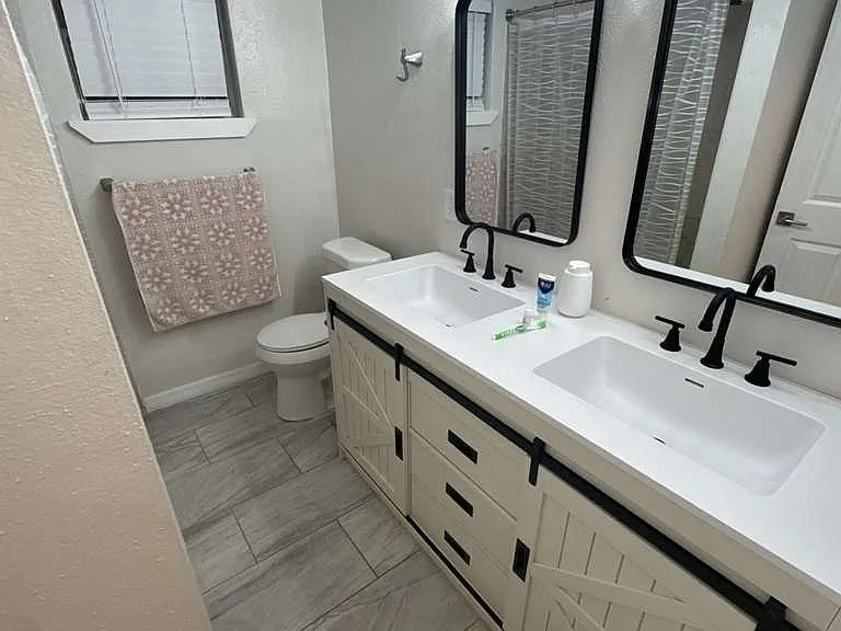 Spacious double vanity area with white cabinetry and bright lighting.