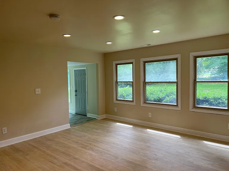 Bright and open living area with modern finishes, fresh paint, new floors, and cozy fireplace charm.