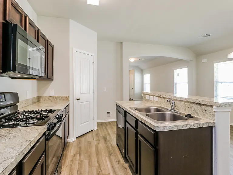 Modern kitchen with sleek dark cabinets, granite countertops, and stainless steel appliances, offering a spacious layout and ample natural light. Modern kitchen with sleek dark cabinets, granite countertops, and stainless steel appliances, offering a spac