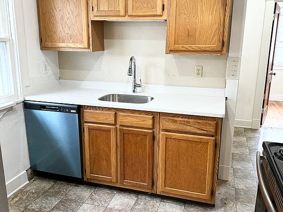 Kitchen with brand new countertop, sink, and stainless steel dishwasher (the film hasn't even been pulled off the dishwasher yet!).