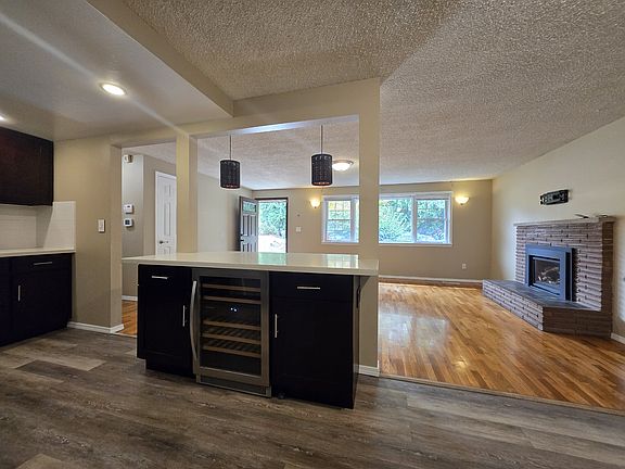 View of living room from the open kitchen. Large eat-in bar has beverage fridge and more cabinetry.