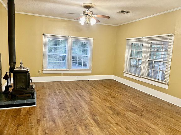 Freshly painted large living area with custom blinds and wood burning stove. Living area is open to the dining area