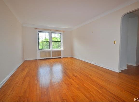 The living room has treetop views and overlooks the quiet courtyard. There are two arched opening, o