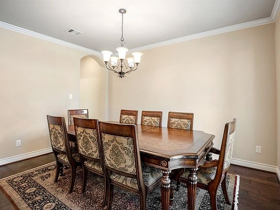 Elegant formal dining room with stunning wood floors, neutral paint tones and crown molding.