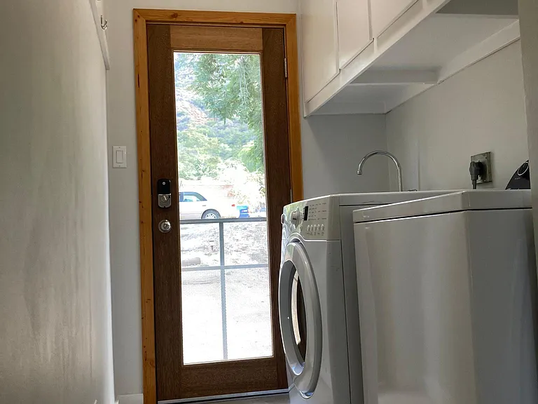 Laundry with Energy Star and Water Wise appliances, plenty of cabinet storage, utility sink with handheld shower head, full glass exterior door and screen door.