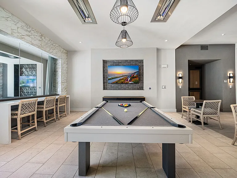 Game lounge with billiards table, bar seating, and mounted TVs