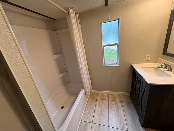 The bathroom has a shower and tile on the floor.