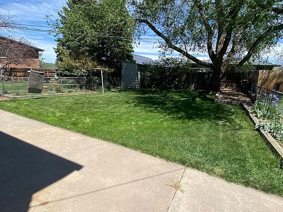 Fenced in backyard has 2 flower beds on each side and plenty of shade.