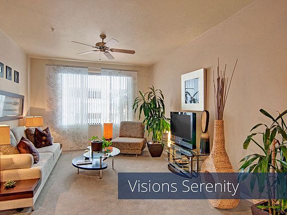 A living room with tall windows and a ceiling fan