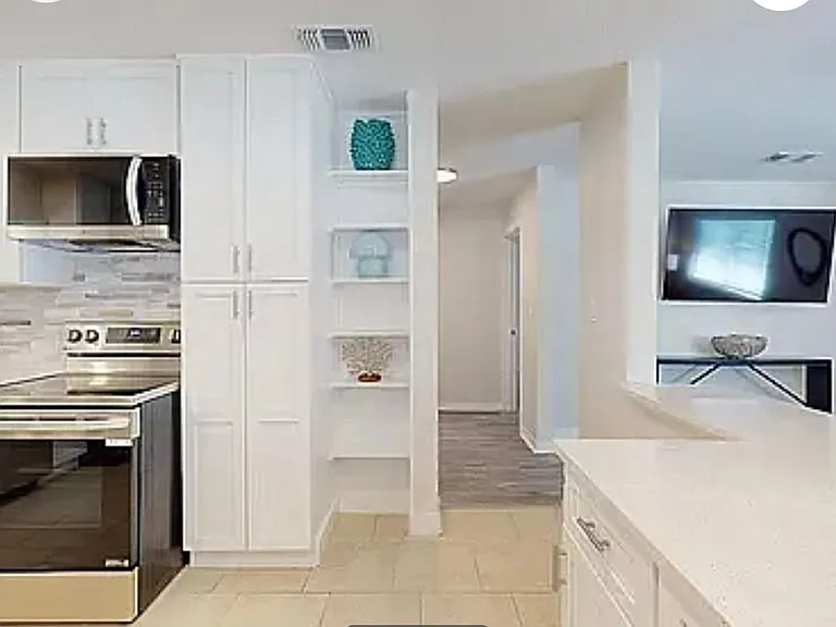 Spacious kitchen with ample cabinet space, stainless appliances, and pass-through to dining and living areas
