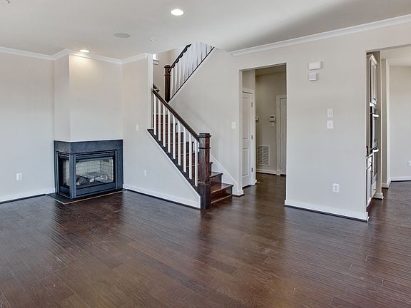Spacious living room with medium toned wood floors, corner fireplace and recessed lighting.