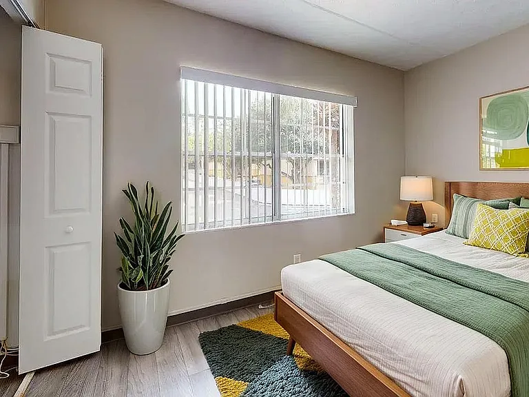 Bright and inviting bedroom with a modern green theme, featuring a comfortable bed, large window with natural light, and stylish decor.
