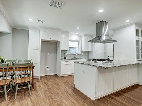 Kitchen with large island that has front storage cabinets and an overhang to accommodate several bar stools.