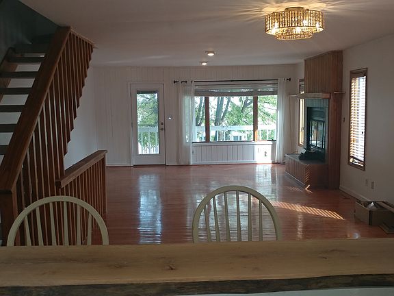 Living/Dining room with wood burning fireplace and balcony facing the bay