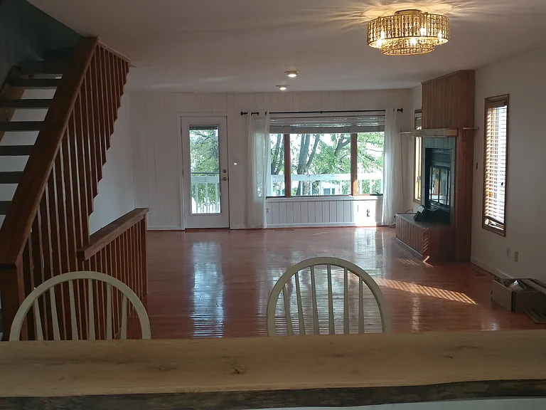Living/Dining room with wood burning fireplace and balcony facing the bay