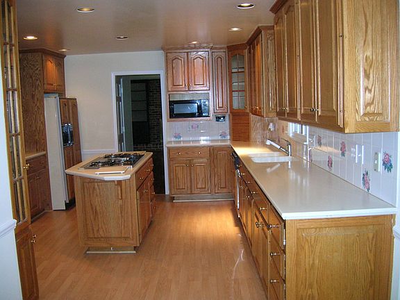 Renovated kitchen with island,corian counters,stained cabinets and wine rack