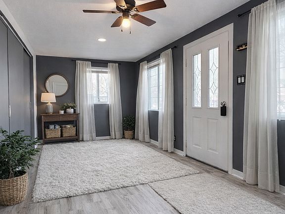 Inviting open space living - dining room with wide-plank flooring, multiple windows for abundant natural light, and a ceiling fan for comfort. The open layout offers plenty of space for relaxing or entertaining.