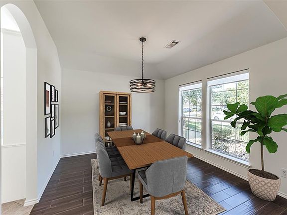 Dining Room is light and bright with windows looking out toward the street. Recent chandelier and solar shades in windows. Archway to left leads into Breakfast Room and Kitchen. Wood-like tile floors in Dining Room. PHOTO VIRTUALLY STAGED.