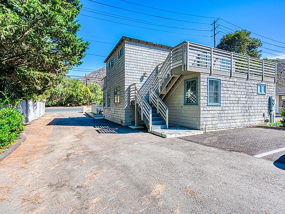 Stairs up to front door and balcony. 2 dedicated parking spaces to the right.