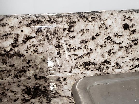 Faux granite countertop, subway tile and stainless steel sink.