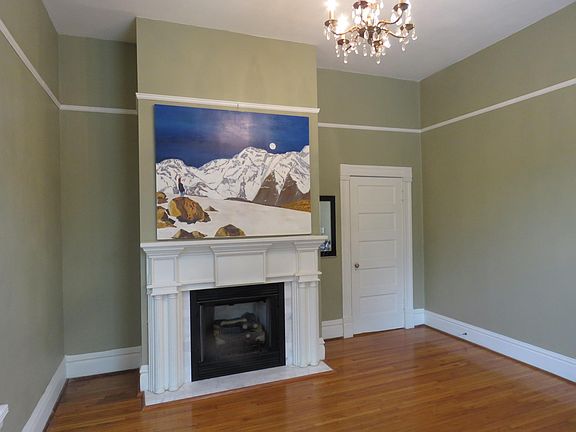 Large living room features gas log fireplace, 11 foot ceilings, hardwood floors and chandelier. Artwork available for tenant use if preferred.