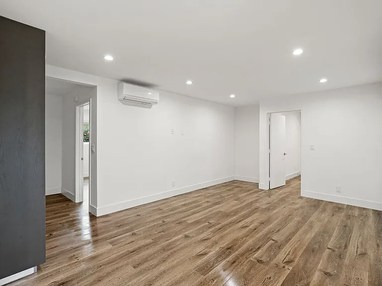 Large Bedroom with Wall Heater, Cabinet Storage, and Window Shades