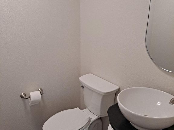 Commode and vanity in half bath downstairs between living room and dining room.