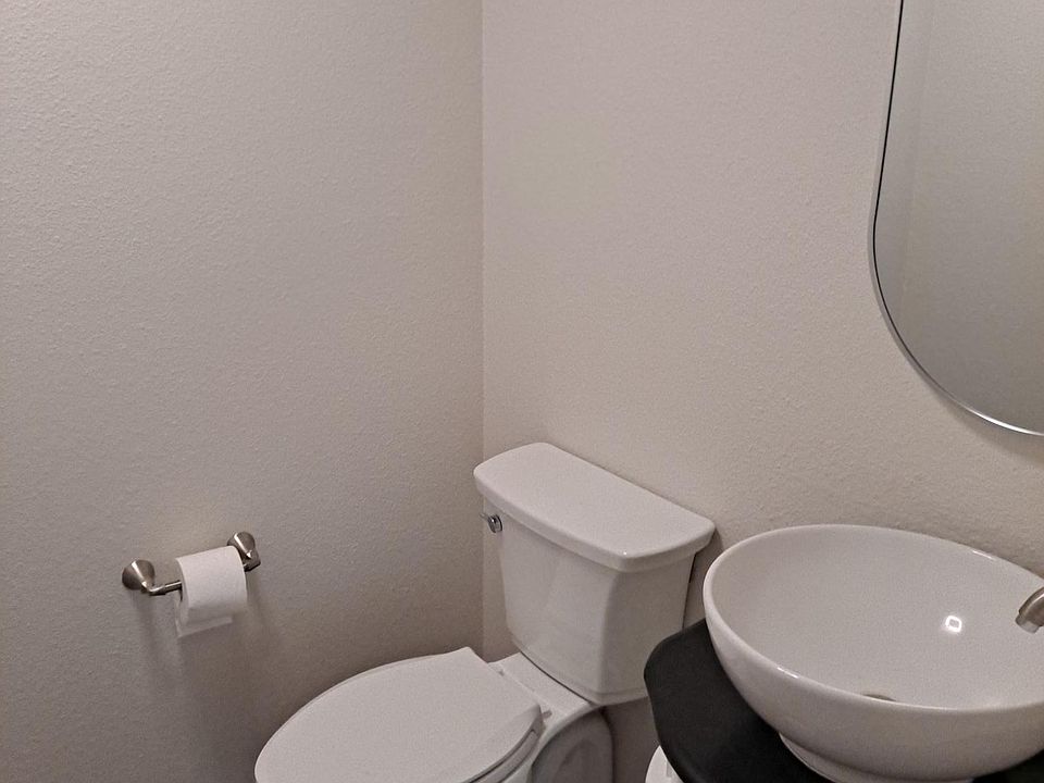 Commode and vanity in half bath downstairs between living room and dining room.