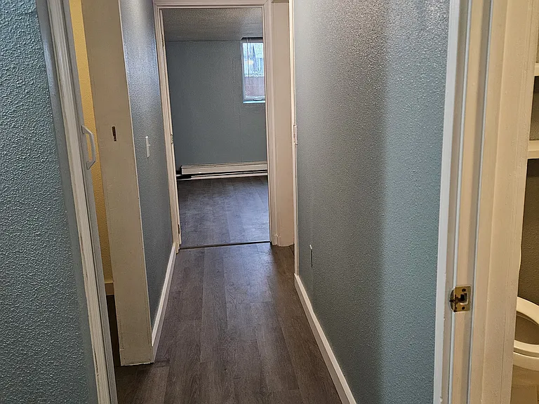 Hallway from kitchen and living room to first bedroom. Bathroom on the right, linen closet on the left, then washer and dryer on the right with the hot water heater.