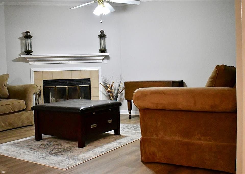 Spacious living area with wood burning fireplace, ceiling fan and gorgeous new flooring.