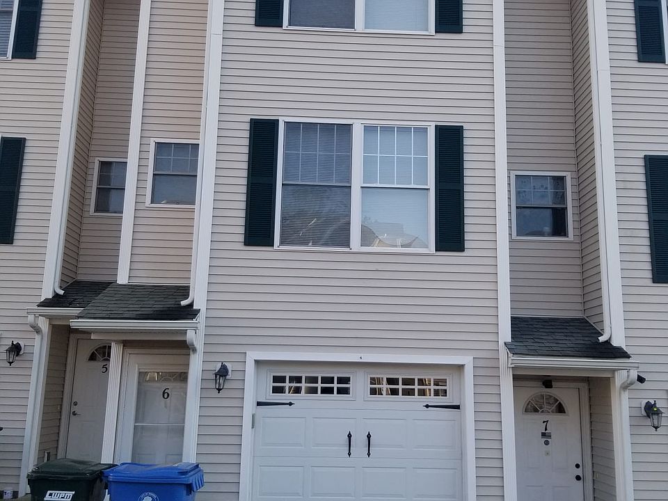 Unit front door and garage door, with garbage and recycling bins.