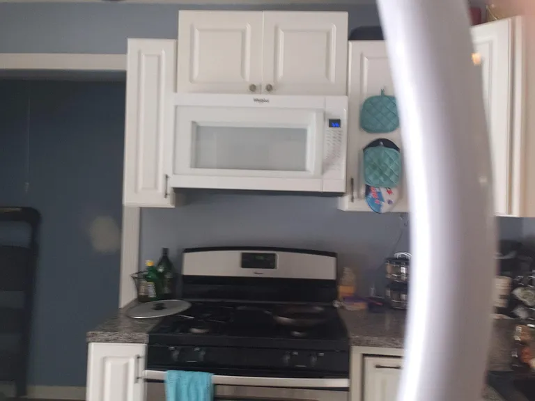 Functional kitchen setup with a full-size range, over-the-range microwave, and ample cabinet storage for daily cooking.