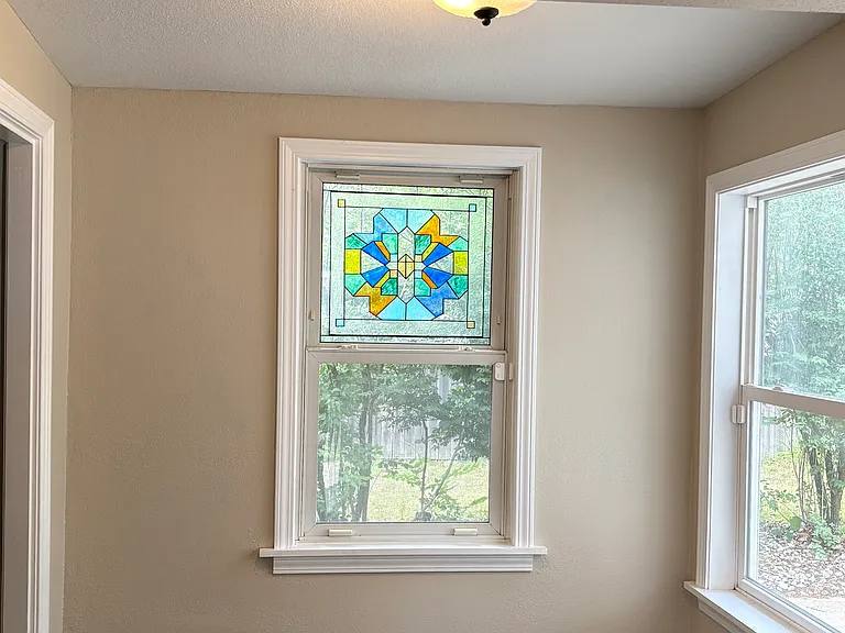 The entryway foyer features a custom-designed faux stained glass piece that sets the tone for the warmth, craftsmanship, and character found throughout the home.