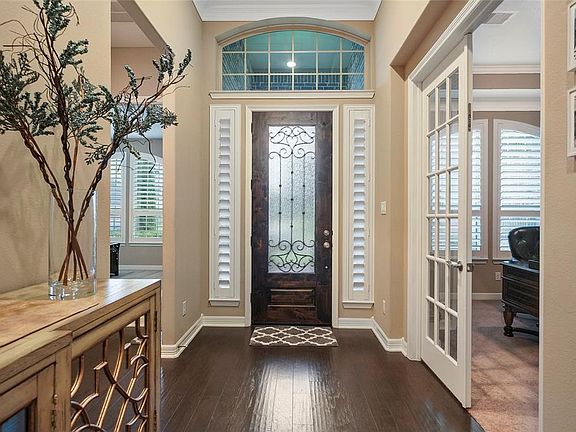 Leaded glass and iron work detail the extra tall front door and Plantation shutters cover the sidelites. The entry is welcoming with its gorgeous wood floors, tray ceiling and 12 foot height. To one side is the office with french doors and to the oth