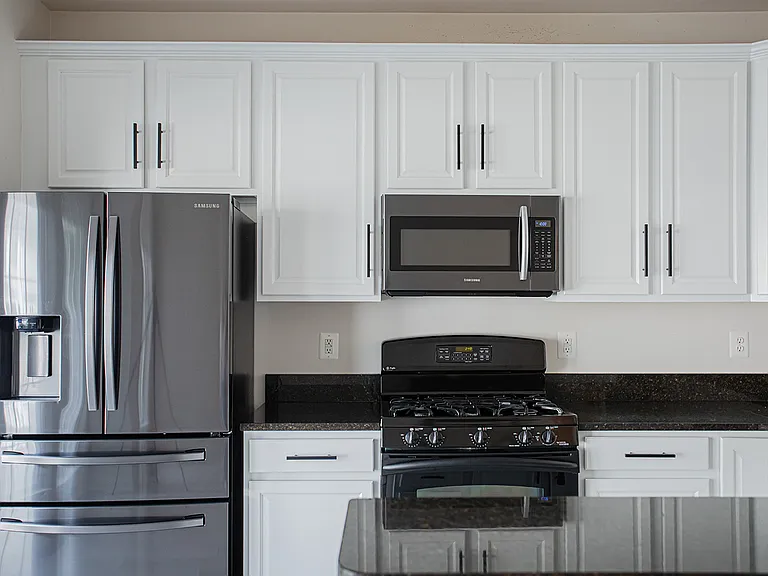 Modern Sleek Kitchen featuring granite countertops and updated stainless steel appliances. Gas stove and functional fridge