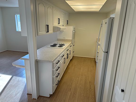 Galley Kitchen with wall oven, electric range, dishwasher, and refrigerator.