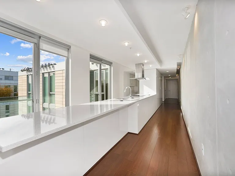 This bright and streamlined kitchen features premium finishes, an extended island, and abundant natural light through full-height windows.