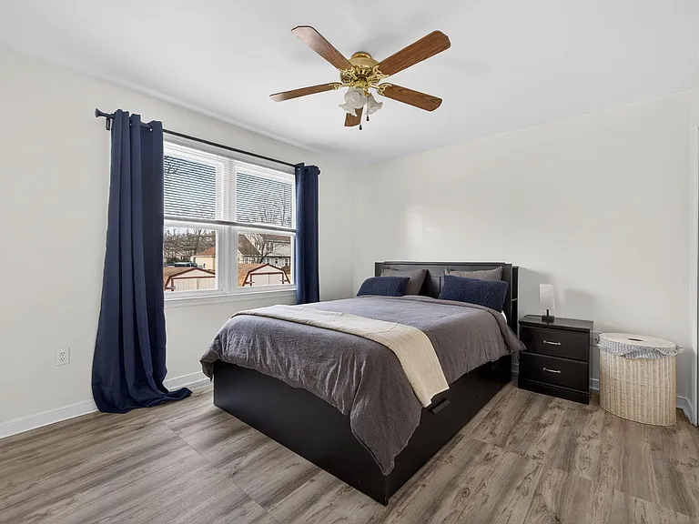 Spacious bedroom with a large window, ceiling fan, and generous closet storage, plus room for a full bed and nightstands.