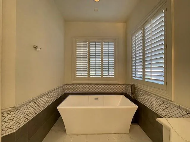 Full bath with wainscoting, a freestanding tub, and tile walls