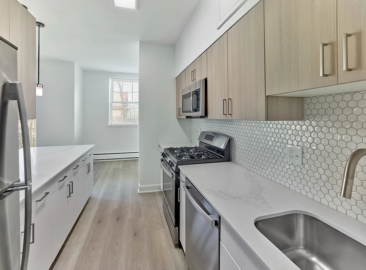 Modern galley-style kitchen with quartz countertops and stainless steel appliances at Crestwood Apartments in Wayne, PA - Crestwood