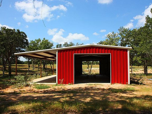 Great red barn with two garage door entrances and covered patio.