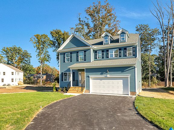 Blue two-story house with attached garage on Lot 29, Poplar Village, featuring a driveway and green