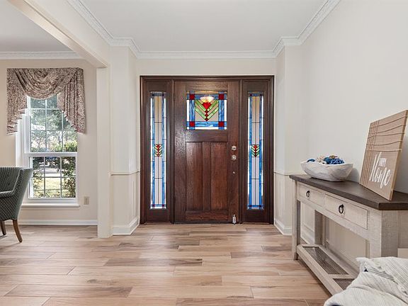 The stained glass side lights usher in natural light highlighting the varied tones in the wood-look ceramic tile.