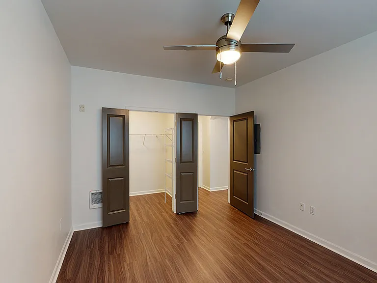 Spacious apartment bedroom with large closet and wood-style flooring.