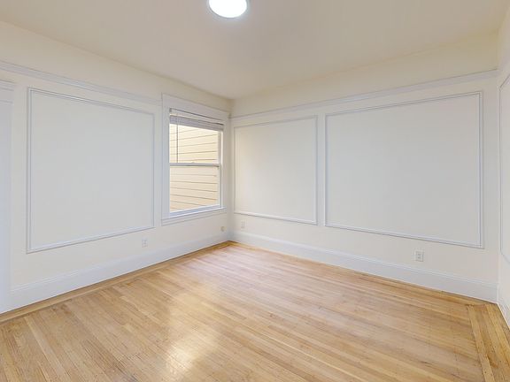 Spacious room with wood-like flooring and a window offering natural light