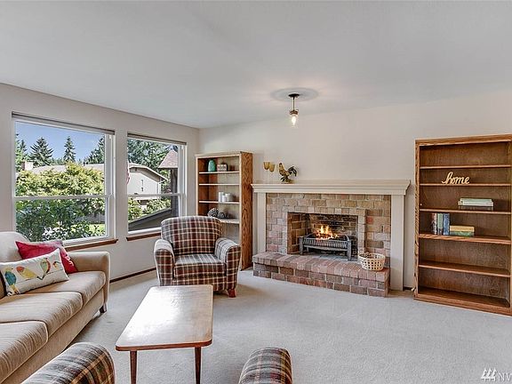 The spacious living room enjoys huge windows, loads of natural light and a lovely brick fireplace. Downstairs carpets are brand new, and upstairs carpets will be replaced prior to close. 