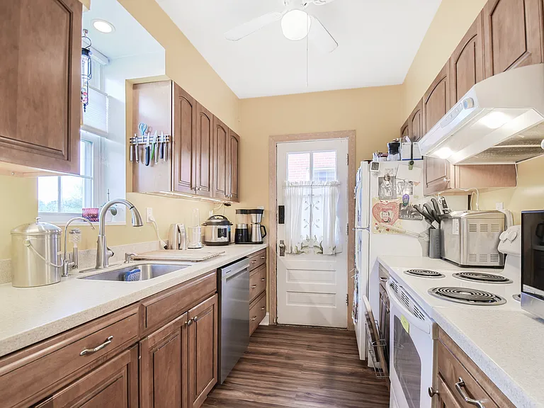 kitchen from south entry way showing stainless steel sink and dishwasher (new Feb 2025). Electric cooktop and oven.